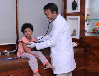 Pediatric doctor checks a young girl's heartbeat with a stethoscope during a clinic visit.