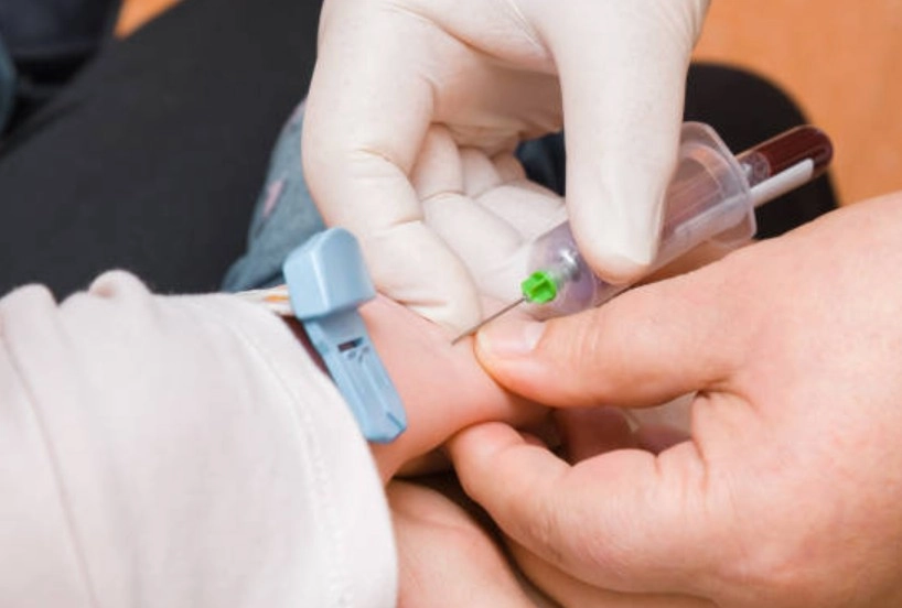 Pediatric Blood Collection Services - Sparsh Hospital - Sparsh Hospital Close-up of a fingertip being pricked for a blood test with a small lancet, while another hand stabilizes the finger (medical procedure).