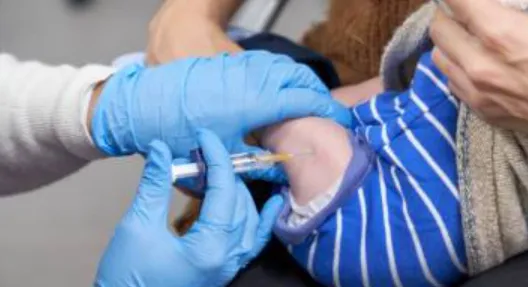 Vaccination of Infants - Sparsh Hospital - Sparsh Hospital Healthcare worker in blue gloves giving a vaccine injection to a baby's upper arm.