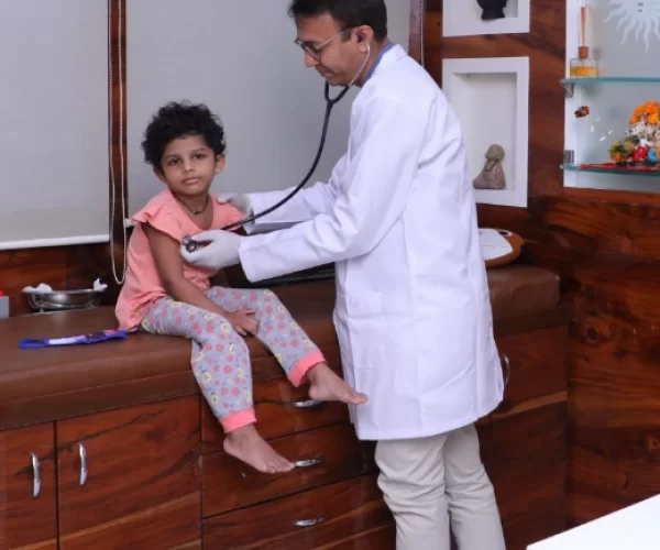 Pediatric doctor listening to a young girl's heartbeat with a stethoscope during a checkup in a clinic setting.